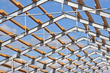 The frame of the roof of the new barn for cows. Construction of a new barn. Wooden beams on a metal frame. Construction of agricultural buildings.