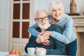 Smiling elderly woman hugging her kind-hearted man