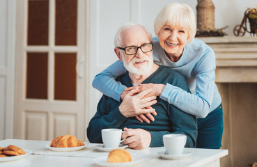 Cute couple of pensioners having warm croissants during breakfast