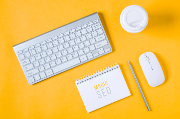 White keyboard, mouse and Notepad on yellow background. Flat lay and top view
