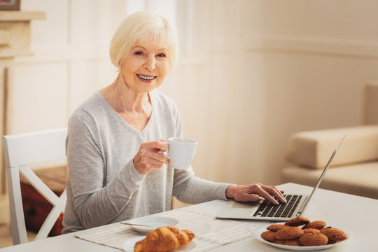 Elderly Woman Eating Biscuits While Typing Business Letter