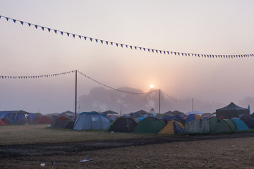 The sun rises over tents and trees at a music festival