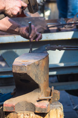 blacksmith performs the forging of hot glowing metal on the anvil