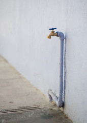 Faucet against old building with lavender pipe