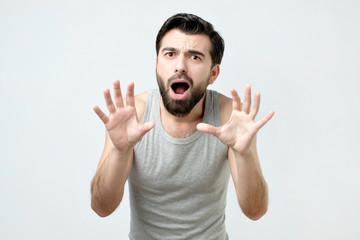 Young man is afraid and terrified with fear expression stop gesture with hands