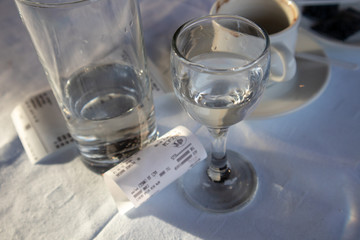 Alcohol drink, cup of coffee and bill on table in restaurant