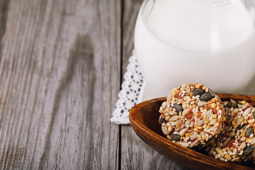 Tasty biscuits from various seeds and dried fruits with milk on a wooden table with copy space