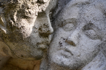 Naklejka premium Partial view of an old, weathered sandstone sculpture. Two faces that are very close to each other.