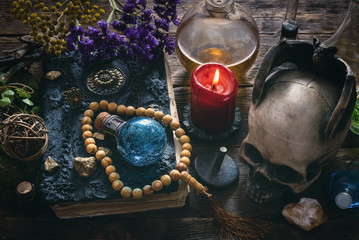 Spell book, magic potions and other various witchcraft accessories on the wizard table background.