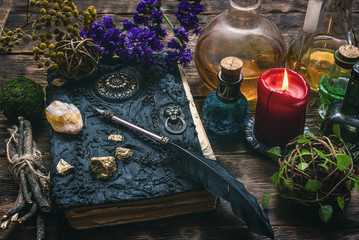 Spell book, magic potions and other various witchcraft accessories on the wizard table background.