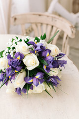 beautiful wedding bouquet of fresh violet irises and white roses on a white table.