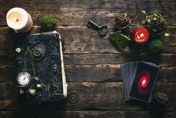 Tarot cards, book of magic and pocket watch on a wooden table background. Future reading.