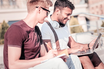 Fototapeta premium Positive foreign student working with his partner