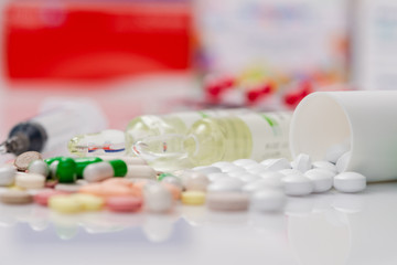 Medicine pills and syringe on white background.