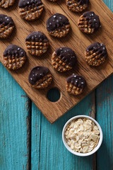Fototapeta premium Raw vegan gluten and sugar free cookies with chocolate and salt served with rolled oats on blue background top view