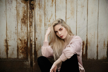 Young blonde woman in bomber jacket sitting outdoors