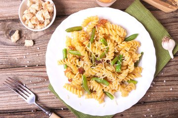 Traditional Italian Sicilian fusilli pasta with bread crumbs and green beans, sprinkled with cheese in a white plate on a wooden background. Tasty food. Top view