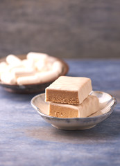 Protein bar in two pieces, creatine capsules and scoop. Bodybuilding food supplements on rustic wooden background. Copy space.