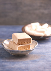 Protein bar in two pieces, creatine capsules and scoop. Bodybuilding food supplements on rustic wooden background. Copy space.