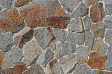 Decorative wall of artificial torn stone in brown tones. Stone masonry in geometric pattern as background or texture.