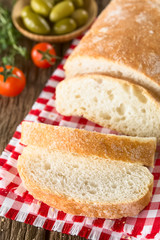 Fresh Italian ciabatta bread sliced, cherry tomatoes and green olives on the side (Selective Focus, Focus on the top of the second slice and the upper part of the first slice)