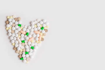 Heart from colorful pills at white background