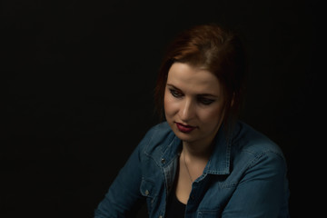 Low key portrait of sad young woman on the black background. 