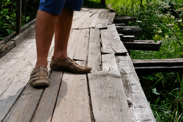 Wooden rural bridge over a river in green woods for tourists to walk along. Wood pathways. Tourist walk.