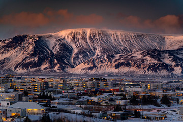 Large mountains rising over Reykjavik City during sunset - obrazy, fototapety, plakaty