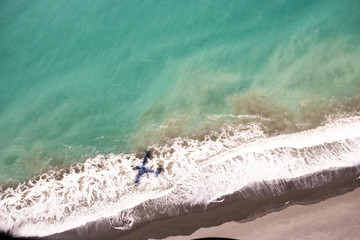 Fototapeta na wymiar Shadow of an airplane over the shore, about to fly over the ocean in Kaikoura, New Zealand