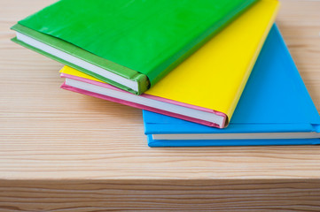Three colorful books on wood background