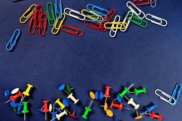 colored paper clips, button  on a dark blue background. 