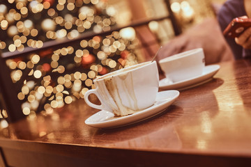 Two cups with spilled coffee on wooden table in a coffee shop, blur background with bokeh effect