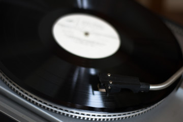The stylus of the vinyl analog player is in contact with the surface of the rotating LP. Close up....