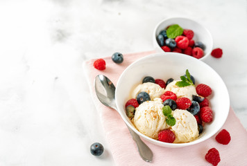 Close up of vanilla ice cream with berries on white table