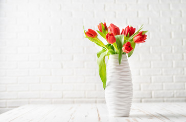 Red tulips in a white vase against the white background