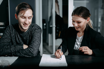 girl colleague explains a business project to a man, a new employee in the office
