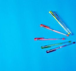 many multi-colored gel pens on a blue background