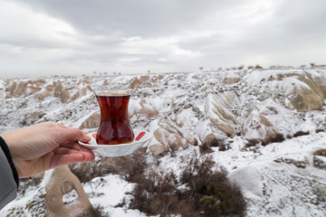 A glass of tea with beautiful winter snow view background for tourism agent concept from Cappadocia pigeon valley.