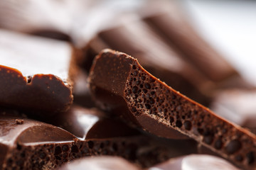 Chocolate broken into pieces. Pieces of tasty dark chocolate on white background