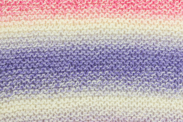 knitted fabric background with garter stitch pattern in pink, purple and white