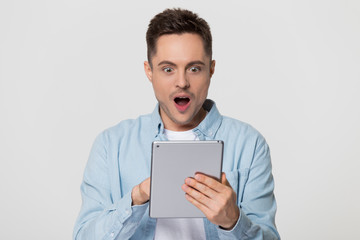 Amazed happy guy using digital tablet excited about online news