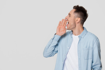 Young man shouting at copyspace making announcement isolated on background
