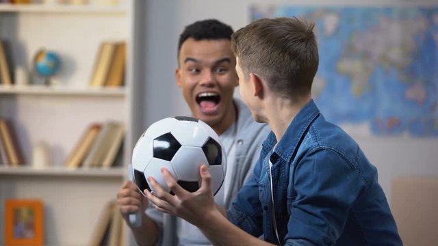 Multiracial male friends cheering for football team, happy with successful match