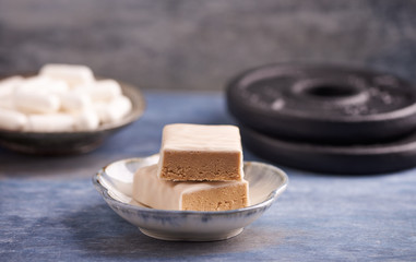 Protein bar in two pieces, scoop and plates.  Nutrition for bodybuilding. Fitness supplements on rustic wooden background. Close up. Copy space