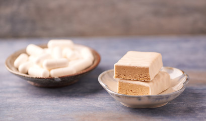 Protein chocolate bar in two pieces and creatine capsules. Bodybuilding food supplements on rustic wooden background. Close up. Copy space.