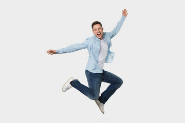 Happy cheerful young man jumping feeling joy isolated on background