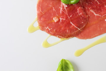 beef carpaccio on a light gray basil background