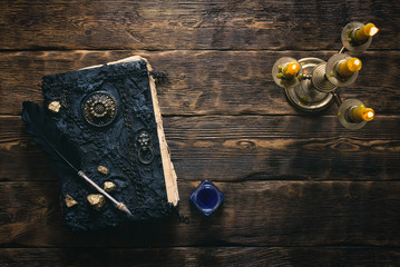 Ancient magic book, inkwell and a quill pen on a wooden table background. Spell book.