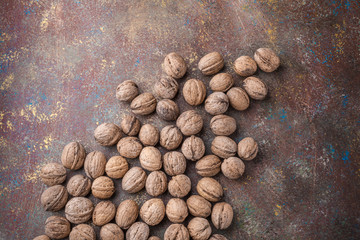 Walnuts large arrangement in shell spilled on painted brown background in studio
